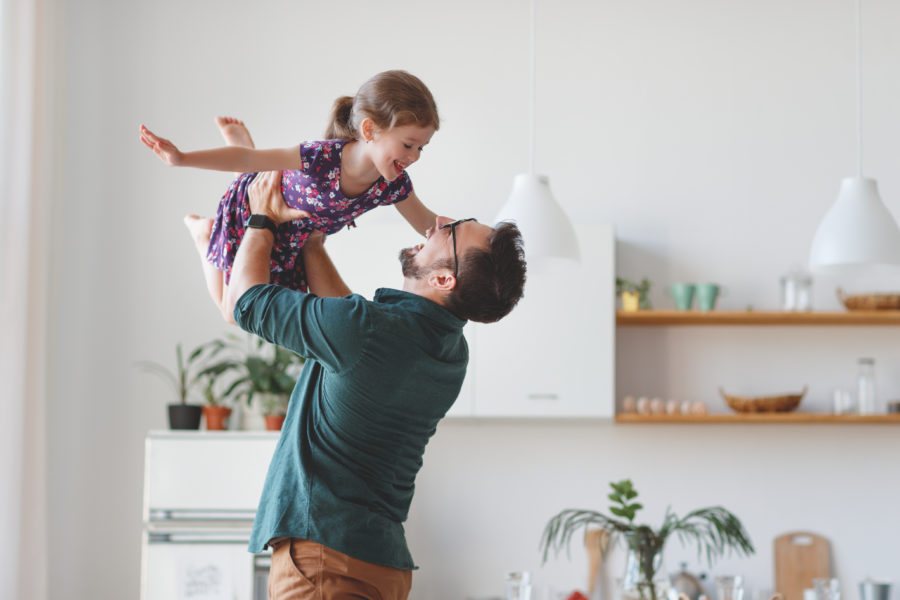 dad playing with his young daughter by throwing her in the air