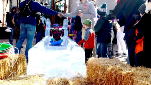 a young child sledding on an ice sculpture at a fun gathering