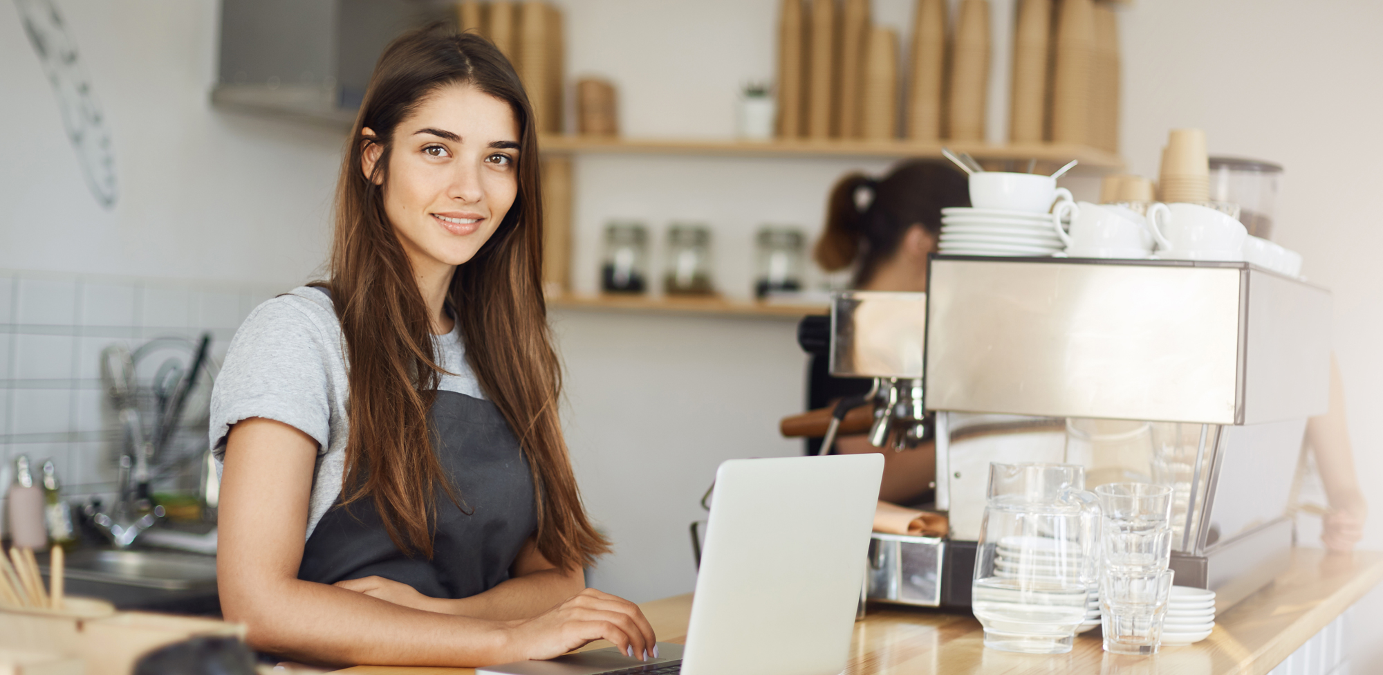 woman coffee shop worker on laptop smiling