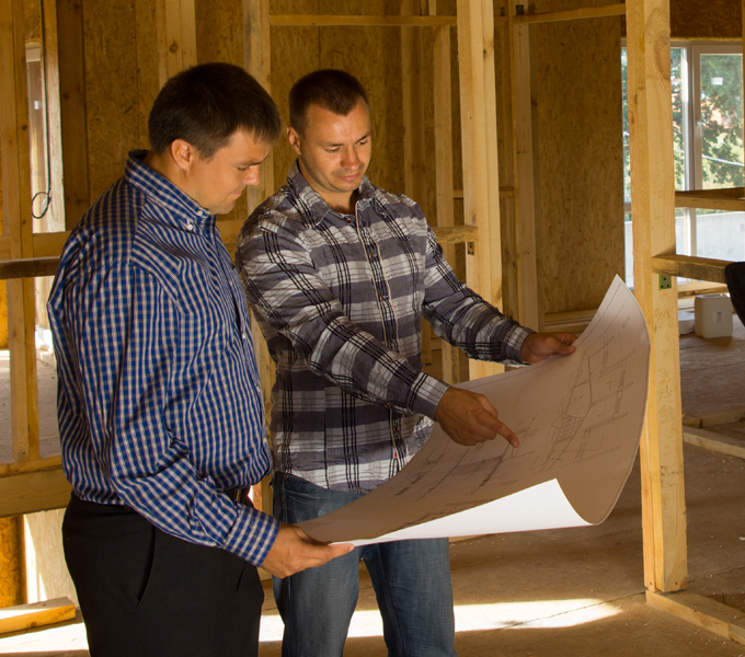 two men looking at home plans inside unfinished home build