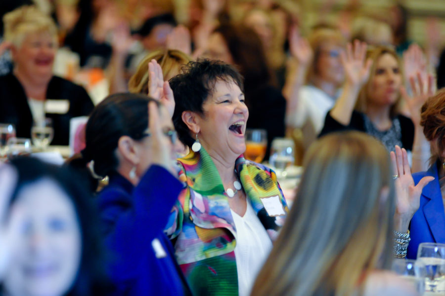 a room full of woman with their hands up