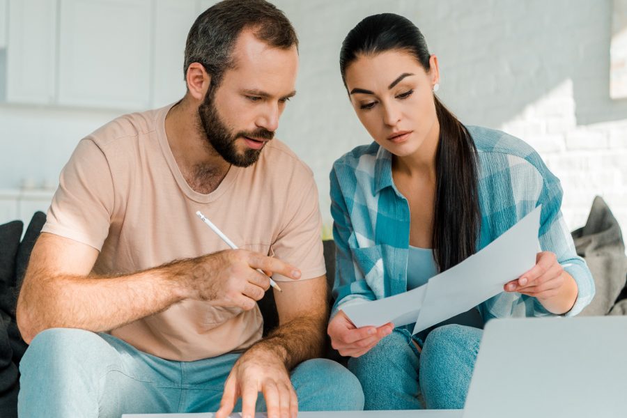 Adult male and female review documents together on a couch in a house