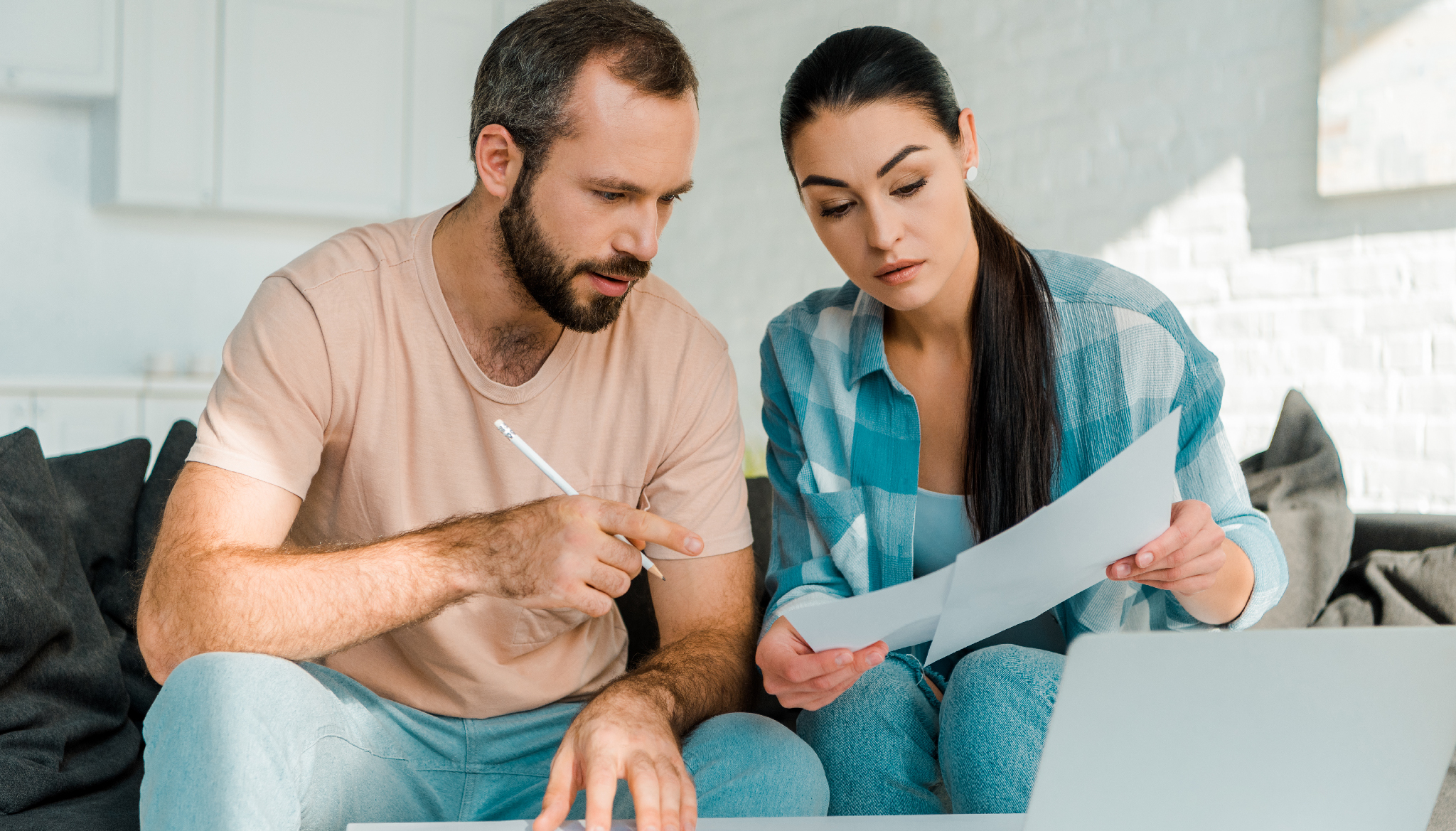 Adult male and female review documents together on a couch in a house
