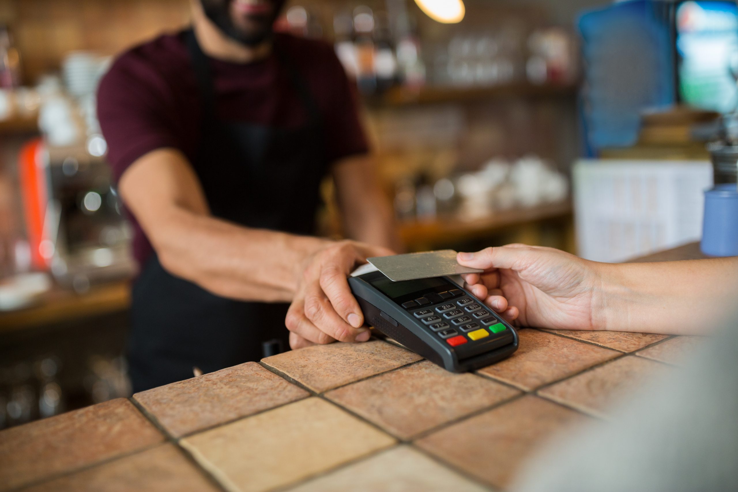 person with payment terminal and customer hand with credit card at business