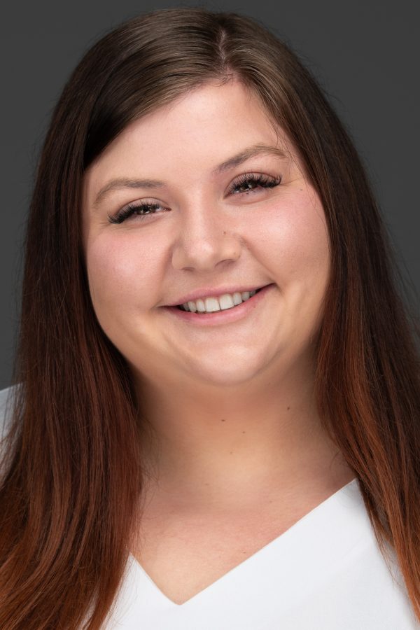 Young woman smiling for professional headshot with gray background