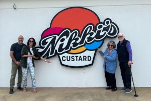 A father and mother, along with their daughter and son-in-law posing in front of the daughter's custard business