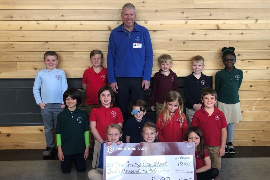 Man presents a donation check with children at an elementary school