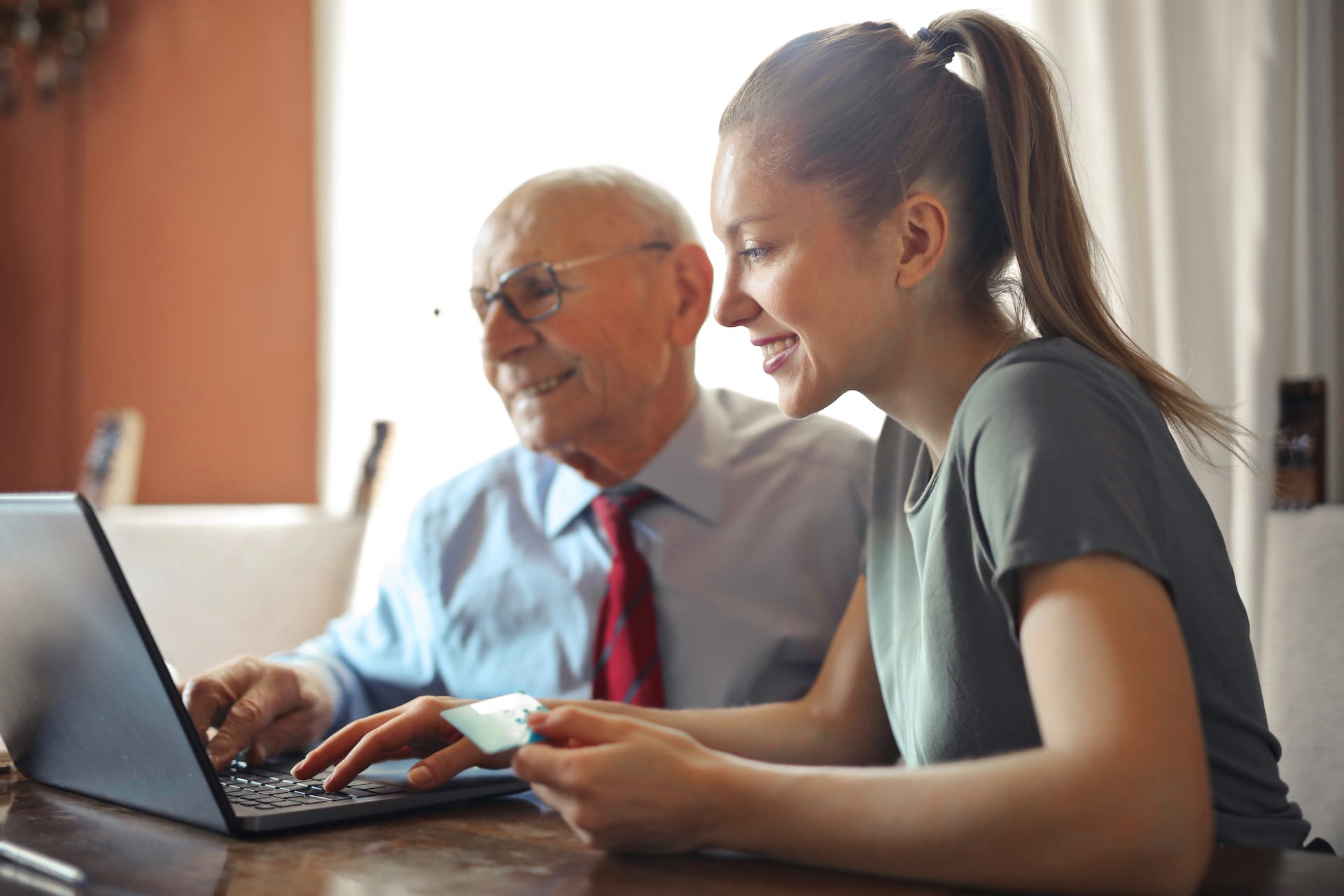 young adult woman and elderly man working together on a computer